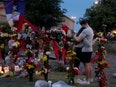Two people embrace in front of a memorial for 8 people shot and killed at a mall in Allen, Texas