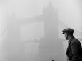 A black-and-white photo of the Tower Bridge, in London, surrounded by fog.
