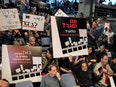 A group of people protest, holding signs in Hebrew.